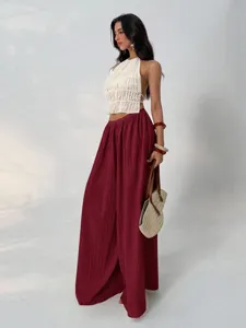 Detailed view of women's wine red pleated wide-leg pants featuring high waist and drape.