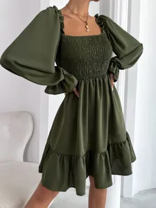 Close-up detail shot of olive green square neck smocked puff sleeve dress with ruffle hem.