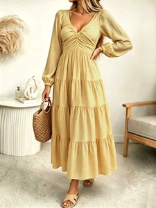 Detailed shot of a French style yellow long sleeve V-neck maxi dress with tiered skirt.