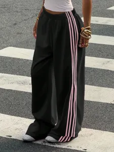 Detail shot of black wide-leg sweatpants with pink side stripes for casual streetwear style.