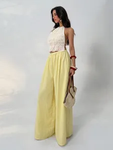 Detail view of the elegant white ruched halter crop top and yellow wide-leg pants outfit.