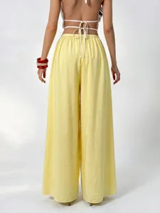 Detail view of backless crop top and high waist yellow wide leg trousers back design.