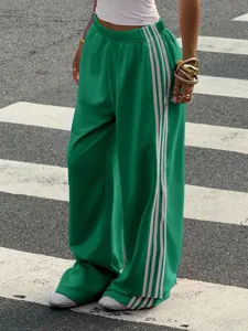 Detail view of green wide-leg knit track pants featuring side contrast striped panels.