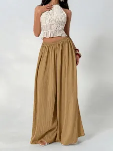 Detailed view of pleated high waist wide leg pants paired with chic white halter top outfit.