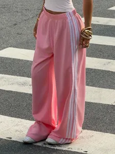 Pink wide leg track pants detail showing white side stripes and casual loose fit style.