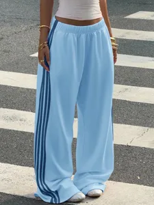 Detail shot of light blue wide leg sports pants featuring dark blue side stripes and loose fit.