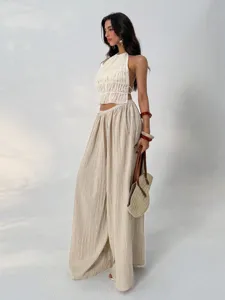 Detailed view of women's pleated wide-leg pants and halter top outfit, elegant drape design.