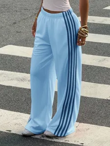 Detail view of casual light blue wide-leg sweatpants featuring contrast side stripe design.