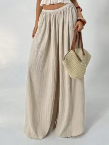 Beige crinkled wide leg pants featuring high elastic waist and elegant draping effect.