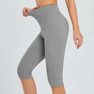 High waist grey capri yoga leggings detail view, featuring side pockets and stretchy slim fit.