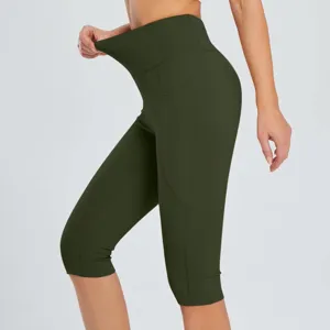 Close-up detail of high-waisted dark green yoga capris showing stretch and side pocket design.