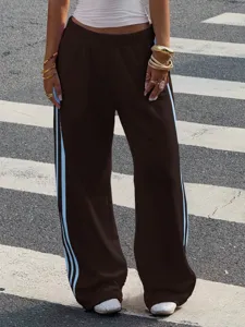 Detail view of brown wide-leg knit track pants featuring contrast light blue side stripes.