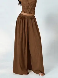 Close-up details of brown pleated wide-leg pants with elastic high waist for casual wear.
