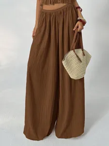Detailed view of women's brown pleated high waist wide leg pants set with elegant drape and style.