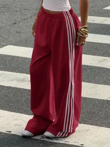 Detail of women red wide leg track pants with white side stripes streetwear fashion.
