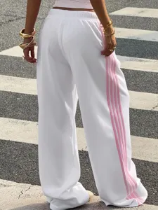Detailed view of women's loose white knit wide-leg track pants featuring pink side stripes.