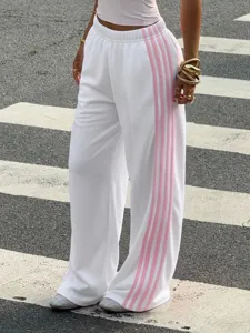 Detail shot of white wide-leg knit sweatpants featuring pink side stripes, casual style.