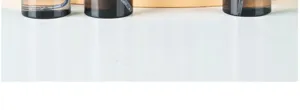 Detailed view of amber travel spray bottles showing fine mist mechanism on white desk.