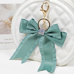 Pleated ribbon bow bag charm with sparkly rhinestones and gold keychain for stylish women accessories.