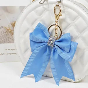Close-up detail of blue fabric bow bag charm with sparkling rhinestones and gold hardware.