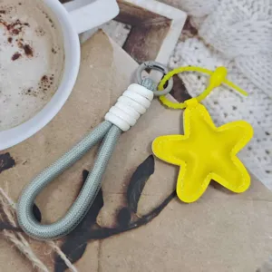 Close-up detail of the grey braided rope phone lanyard featuring a bright yellow star leather pendant.