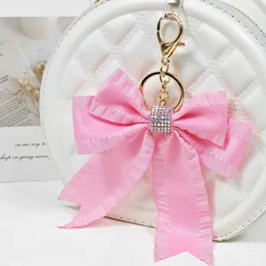 Pink ribbon bow bag charm with shiny rhinestones, gold keychain pendant for women and girls.