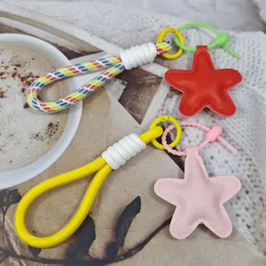 Close-up detail of colorful braided phone lanyard and cute star keychain strap accessory.