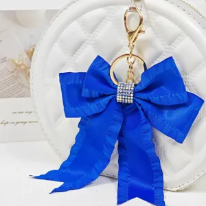 Blue ribbon bow keychain detail, featuring shiny rhinestones and pleated streamer design.
