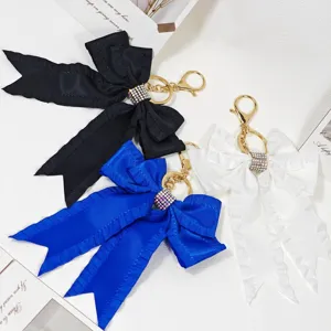 Ribbon bow keychain with sparkling rhinestones and gold hardware, stylish bag charm pendant.