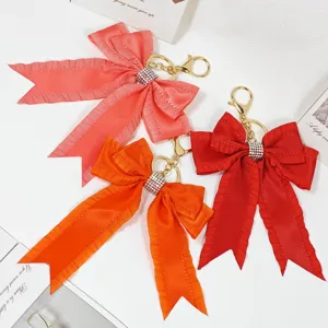 Pleated ribbon bow keychain with shiny rhinestones, stylish bag pendant accessory.