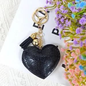 Détail du porte-clés cœur en strass étincelant avec ses cristaux noirs et son pompon élégant.