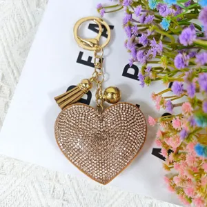 Gros plan détaillé d'un porte-clés cœur en strass étincelant avec pompon et breloque dorés.