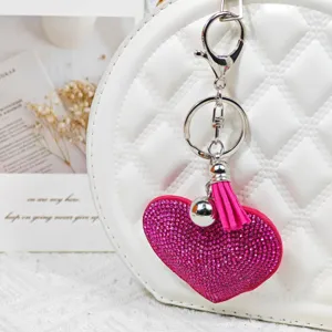 Détail de porte-clés cœur en strass avec pompon rose et fermoir en métal pour sac élégant.