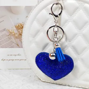 Gros plan détaillé d'un porte-clés cœur en strass bleu scintillant avec pompon et clochette.