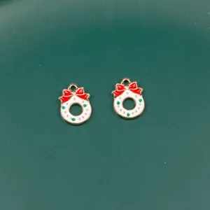 Close-up detail of Christmas wreath metal charms with red bows for DIY jewelry making.