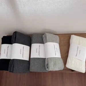 Detailed view of solid color ribbed cotton tights with neat paper band packaging details.