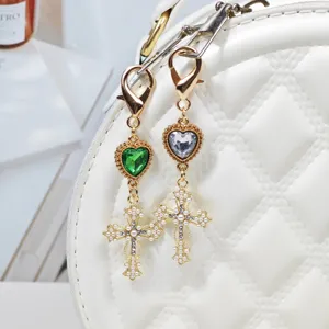 Close-up detail of luxury gold alloy cross bag charm featuring pearl and gemstone accents.