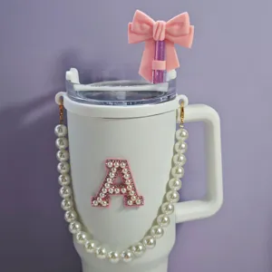 White tumbler with pink bow straw cover, pearl letter A patch and pearl chain handle design.