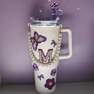 Primo piano di decoro per tazza fai da te con catena di perle, patch farfalla e fiore.