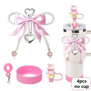 Pink tumbler accessories set with pearl bow keychain, silicone boot, and cute bear straw topper.