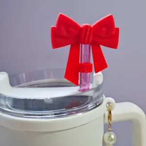 Detailed close-up of a cute red silicone bow straw topper with a glitter straw on a white tumbler.