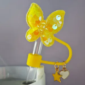 Primo piano del grazioso copripaglia a farfalla con paillettes gialle e ciondoli a cuore.