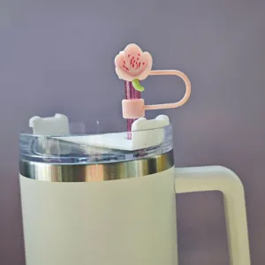 Detailed view of a cute pink cherry blossom straw cover with transparent lid and white tumbler.