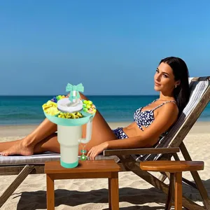 Detailed scene showing a portable snack tray and straw cap on a tumbler at a beach.