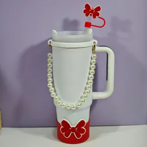 Gobelet isotherme blanc avec sangle en perles, protection en silicone rouge et paille.