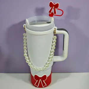Vue de détail du gobelet isotherme avec sangle de perles et accessoire de paille nœud rouge.