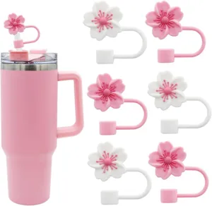 Close-up detail of cute cherry blossom silicone straw caps and pink tumbler, reusable dustproof.