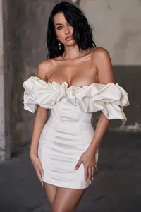 White off-shoulder corset mini dress with dramatic ruffled sleeves and structured boning detail.