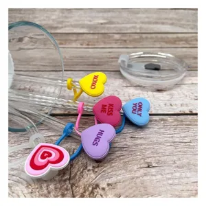 Gros plan de charmants couvercles de paille en silicone en forme de cœur avec des textes doux.