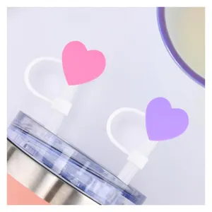 Inquadratura di dettaglio di coperture per cannucce a cuore in silicone, antipolvere, rosa e viola.